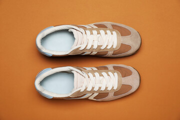 Pair of stylish sneakers on pale brown background, flat lay. Casual shoes