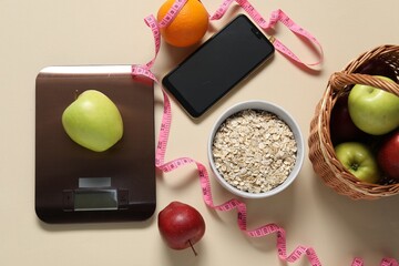 Electronic kitchen scale, measuring tape, smartphone and products on beige table, flat lay. Diet