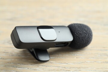 Lavalier microphone on wooden table, closeup. Audio equipment