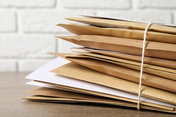 Stack of different paper envelopes on wooden table, closeup. Post office