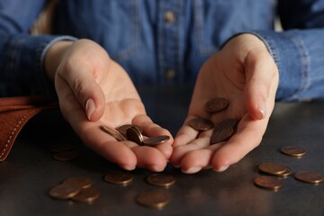 Upset woman counting coins at grey table, closeup. Financial problems