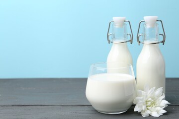 Fresh milk and flower on wooden table against light blue background. Space for text