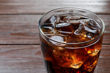 Refreshing cola in glass on wooden table, closeup. Space for text