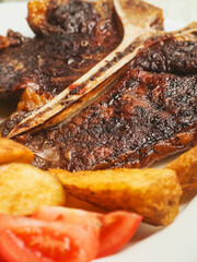Cooked beef T bone steak meal. Premium high quality meat served on a plate with wedges and fresh...