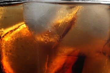 Refreshing cola with ice as background, macro view