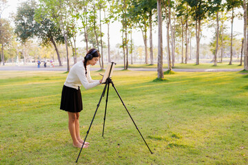 Surrounded by the warm glow of sunset, a young female student listens to music and joyfully...