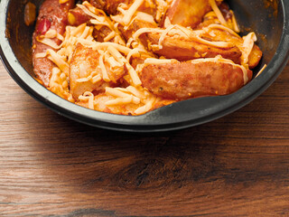 Ready made dish with wedges, garlic sauce and cheese in plastic tray on wooden table surface. Fast food made of high quality products ingredients. Lunch for cooking in microwave.