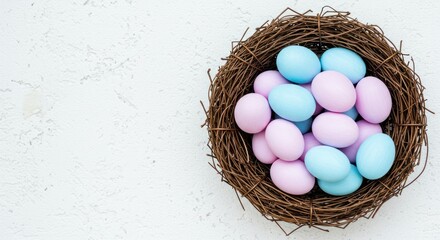 Bird nest filled with blue and pink pastel eggs on white background.