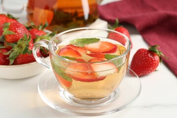 Aromatic fruit tea with strawberries and mint on white marble table, closeup