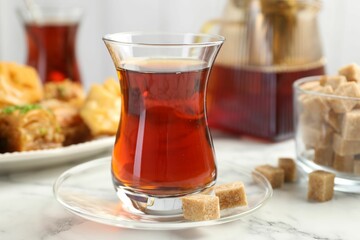 Tasty Turkish tea served with sweets on white marble table, closeup