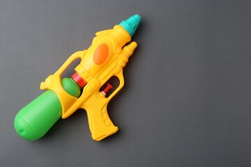 Bright plastic water gun on grey background, top view. Space for text