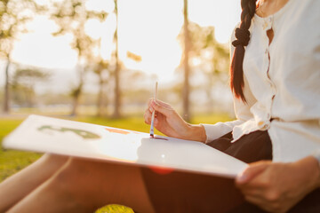 A quiet moment of creativity—sketching on white paper as the warm golden evening light gently bathes the scene