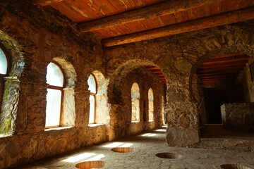 Fototapeta premium Traditional Georgian wine cellar with sunlit arched windows and underground clay vessels (qvevri) embedded in the stone floor. Historic winemaking architecture in the Kakheti region