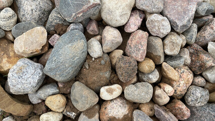 large and small stones close-up laid out on a city path, park decoration, pink and gray pebbles