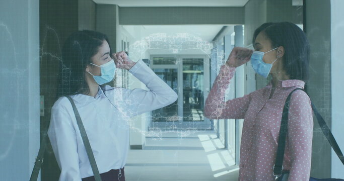 Image of spinning human brain over businesswomen wearing face masks