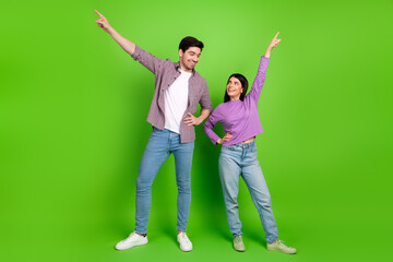 Joyful couple posing with enthusiastic gestures on a vibrant green backdrop symbolizing happiness,...