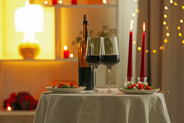 Romantic place setting with red wine and burning candles on table in restaurant