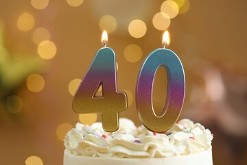 40th birthday. Burning number shaped candles on cake against blurred background with lights, closeup. Bokeh effect