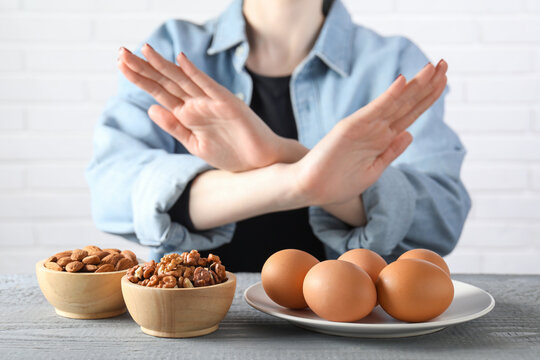 Woman refusing to eat products at grey wooden table, selective focus. Food allergy concept - Powered by Adobe
