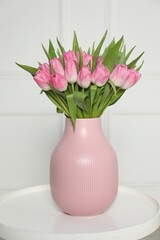 Bouquet of beautiful tulips in vase on white table indoors