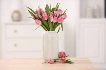 Bouquet of beautiful tulips in vase on wooden table indoors