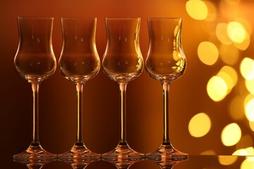 Many clean glasses on glass mirror surface against blurred lights. Bokeh effect