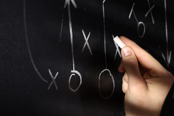 Man drawing American football game scheme on chalkboard, closeup