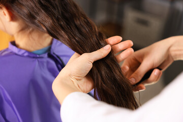 Fototapeta premium Hairdresser combing girl's hair in salon, closeup