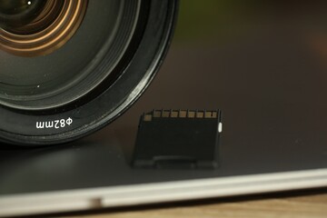 SD memory card, laptop and photo camera on table, closeup