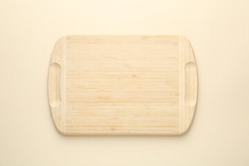 One wooden cutting board on beige table, top view