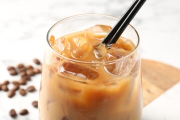 Tasty iced coffee and beans on white table, closeup