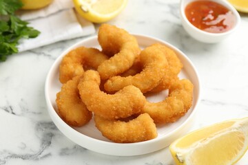 Tasty tempura shrimps and lemon on white marble table, closeup
