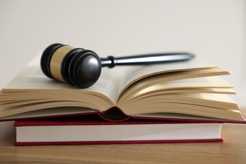Judge's gavel and books on wooden table indoors, closeup