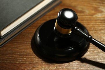 Judge's gavel, sound block and books on wooden table, closeup