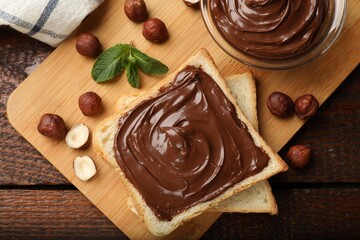 Toast with tasty chocolate hazelnut spread, nuts and mint on wooden table, flat lay