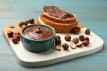 Toast with tasty chocolate hazelnut spread and nuts on blue wooden table, closeup