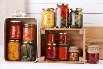 Many jars with different pickled products and ingredients on white wooden table
