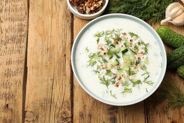 Tasty cucumber soup with dill, nuts and garlic on wooden table, flat lay. Space for text