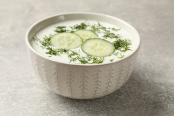 Tasty cucumber soup with dill in bowl on grey textured table, closeup