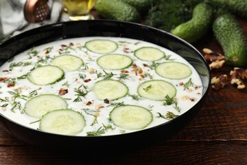 Fresh tasty cucumber soup and ingredients on wooden table, closeup