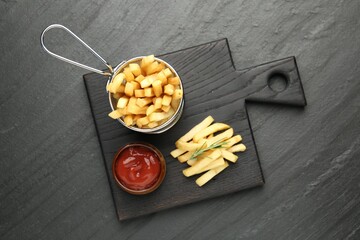 Tasty french fries served with ketchup and rosemary on black table, top view