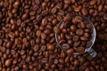 Aromatic coffee beans and glass cup on table, top view. Space for text
