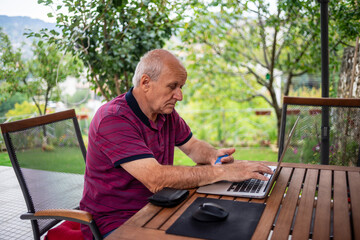 Old Man shopping from web with using laptop on garden