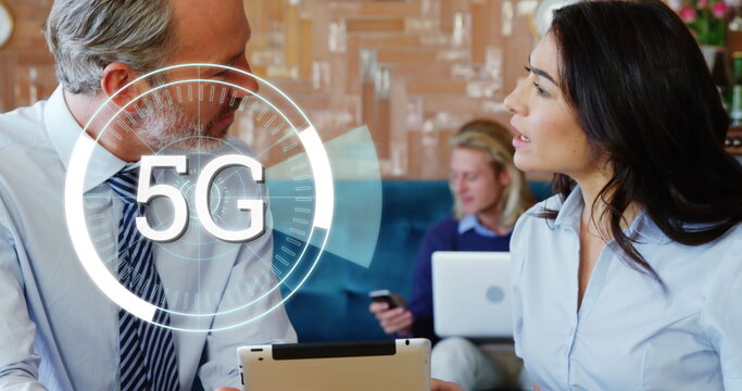 Image of 5g over diverse businessman and businesswoman talking in office