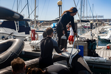 Divers loading scuba tanks onto boat at marina