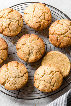 Golden brown cookies cooling on a wire rack with a striped cloth nearby.