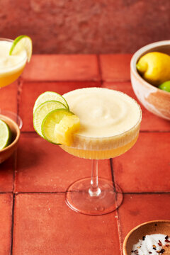 Pineapple Lime Margarita on terracotta tile surface with chilli salted rim