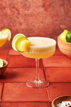 Pineapple Lime Margarita on terracotta tile surface with chilli salted rim
