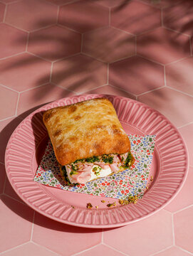 delicious  Italian Mortadella Sandwich with Pesto and Mozzarella basil pesto, crusty ciabatta bread, pink background
