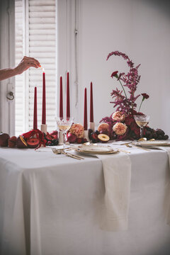 Table Set in elegant style with red hues of fruits, candles and flowers.